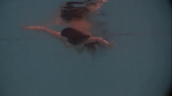 Голая брюнетка купается в бассейне